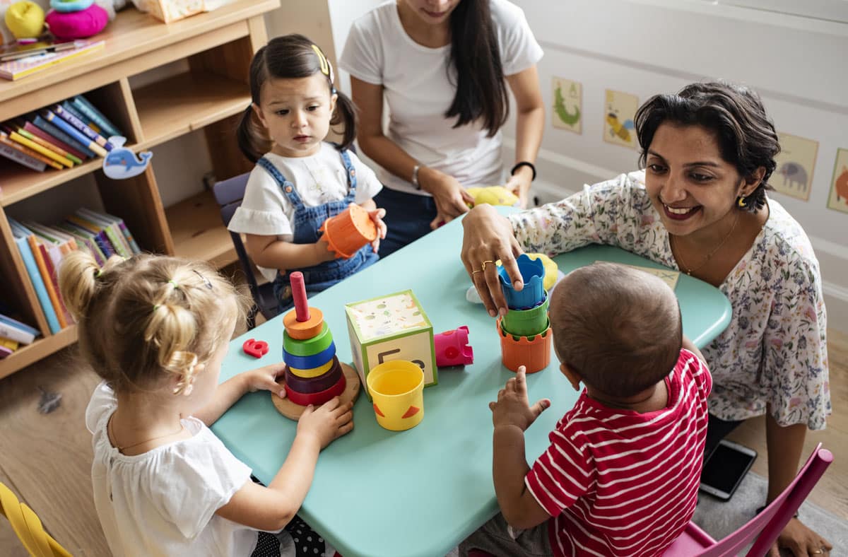 Diverse toddlers learning with their patient teacher at a preschool & child care center Serving Smithfield, RI.