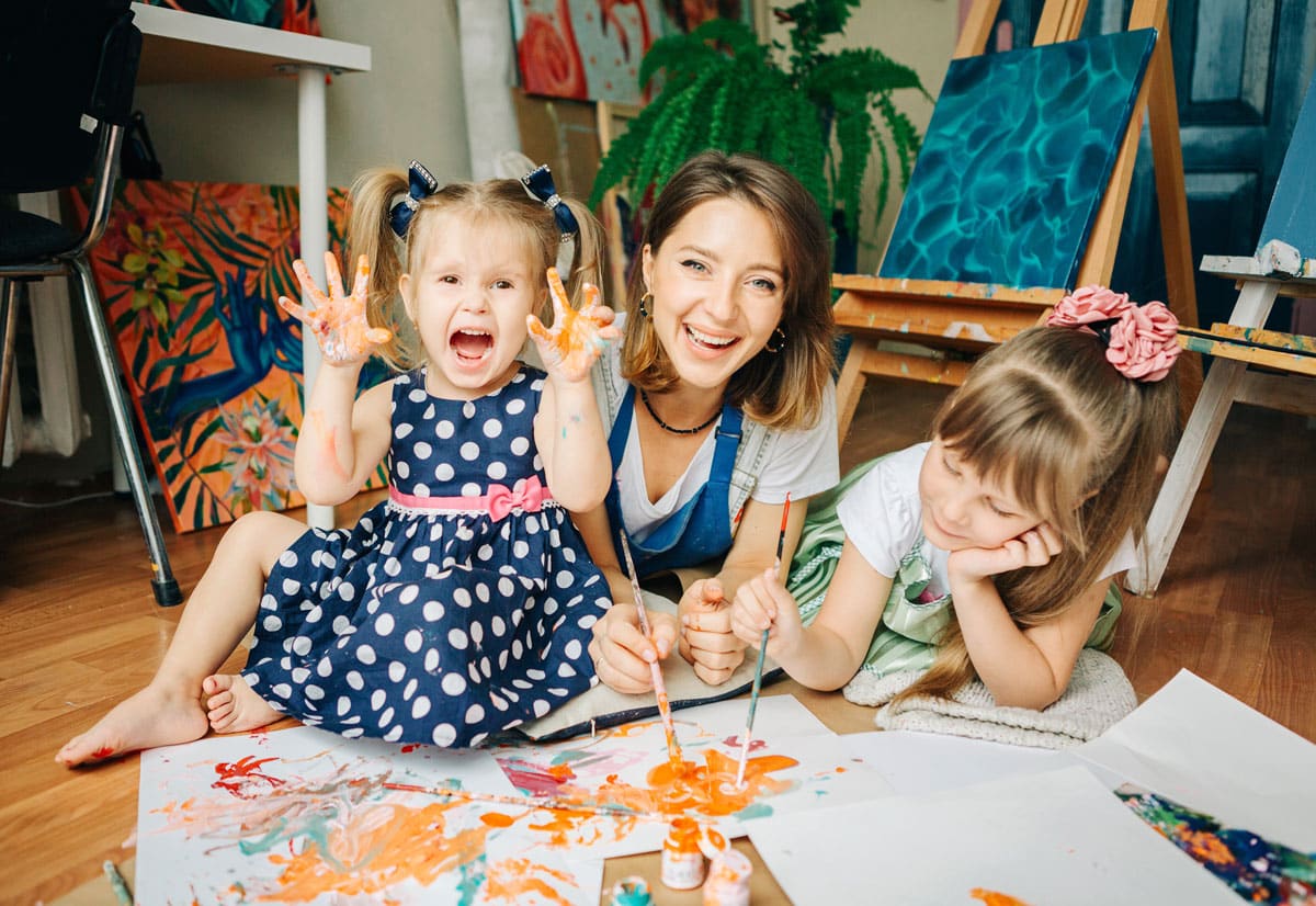 Happy kids painting with their teacher at a preschool & child care center Serving Smithfield, RI.