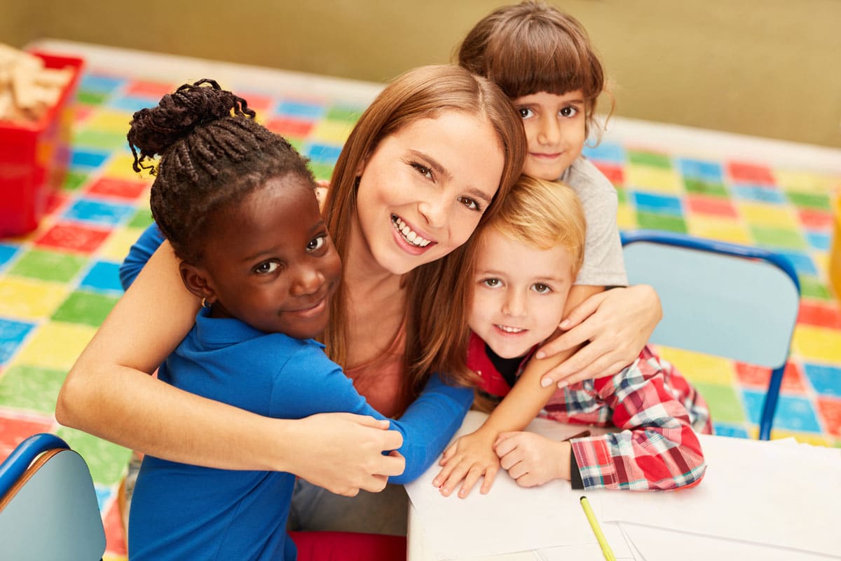 Happy diverse kids with a teacher at a preschool & child care center Serving Smithfield, RI.