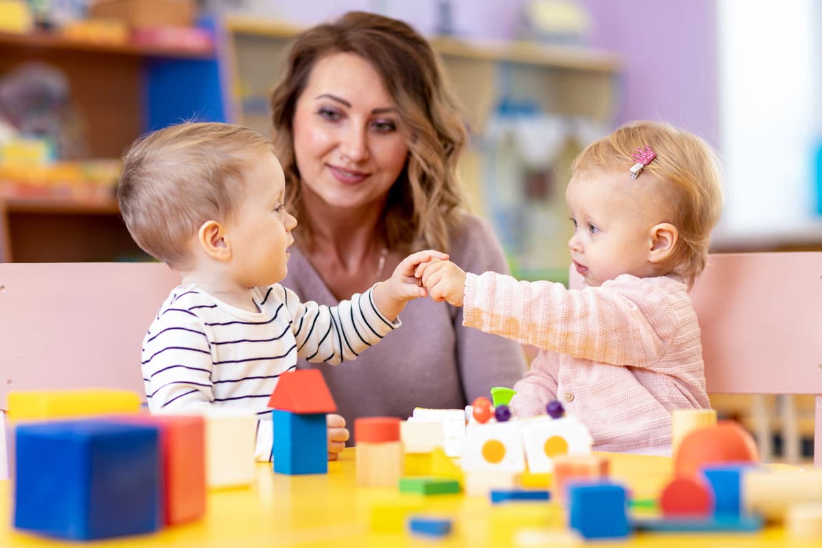 Teacher looking at happy toddlers learning at a preschool & child care center Serving Smithfield, RI.