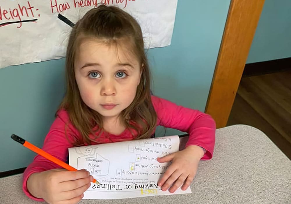 Kindergarten kid learning and writing at a preschool & child care center Serving Smithfield, RI.